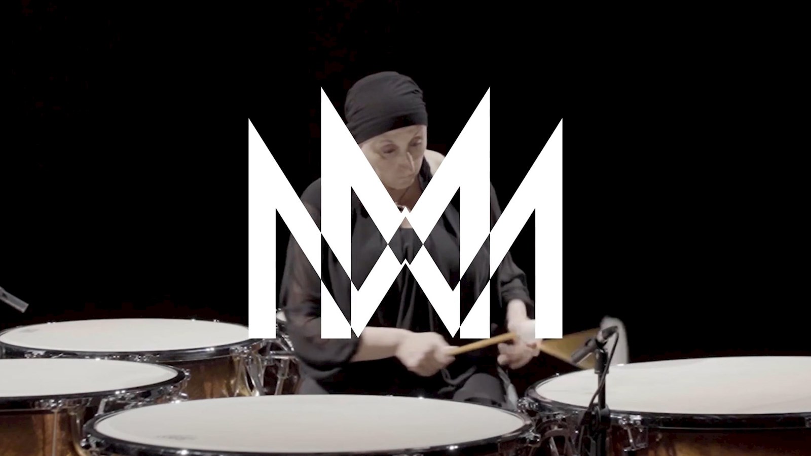 Woman wearing black playing the drums with the Milan Symphony Orchestra logo in white
